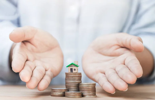 Evi ve sikkeyi veren kişinin eli bu. Emlak, yatırım, ev satın alma konsepti. Mülk, ipotek ve yatırım konsepti. Ev almak için tasarruf.