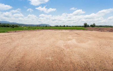 Kuru, çatlak bataklık ıslah toprağı, konut inşaatı için arazi arazi, kırsal alanda araba lastiği izi ve temiz hava ile güzel mavi gökyüzü. Satış arazisi konsepti için arazi..