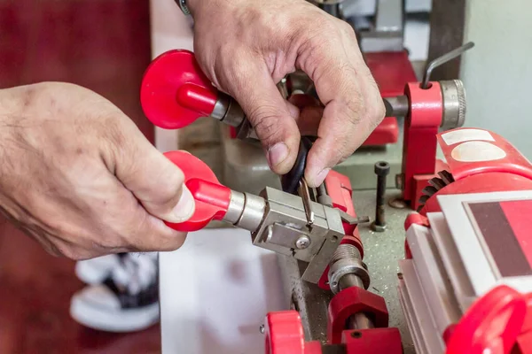 Blur Locksmith in workshop makes new key. Professional making key in locksmith. Machine production of duplicate metal key.