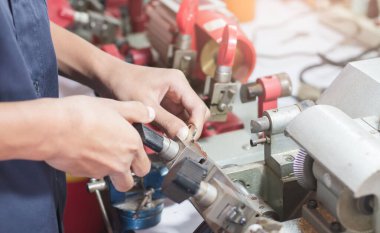 Atölyedeki çilingir yeni anahtar yapıyor. Çilingirde anahtar yapan bir profesyonel. Kopya metal anahtarın makine üretimi.