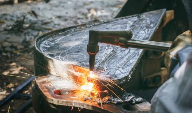 Kapalı el yapımı ağır sanayi işçisi, metal fabrikası işlemleri üzerinde çalışıyor. Gaz kesme makinesiyle çeliği keserek kazan fabrikasında kalın çeliği kesiyor..