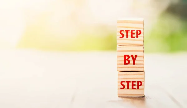 The word step by step on wooden cubes. Achievement or progress in business career. Business growth, career growth or goal concept.