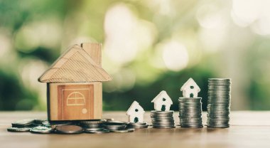 Para ve sikkelerin üzerine yerleştirilen ev ahşap masanın üzerine yerleştirilen merdiven. gayrımenkul merdiveni, ipotek ve emlak yatırımları için konsept satın almak amacıyla madeni paralardan tasarruf parası planlamak.