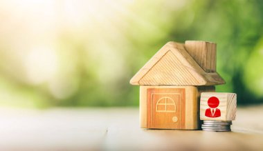 Masanın üzerinde ahşap bir ev var. Emlak komisyoncusunun sembolü, gayrimenkul yatırımı kavramı. gayrımenkul, ipotek ve yatırım için konsept satın almak üzere madeni paralardan tasarruf parası planlamak.