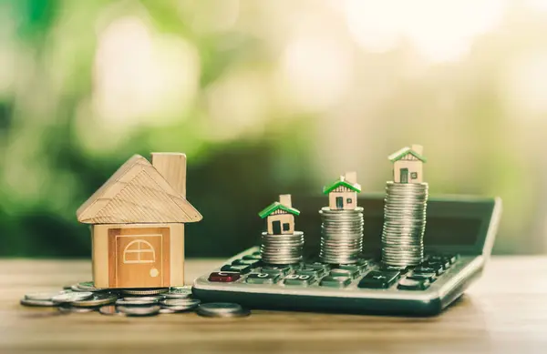 Ev ve madeni paralar hesap makinesine konur. bir konsept, emlak merdiveni konsepti, ipotek ve emlak yatırımı için tasarruf parası planlamak, satın alma evi için tasarruf etmek.