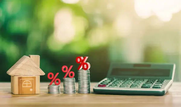 Ev madeni paraların üzerine ve hesap makinesi masanın üzerine konur. Faiz ödemelerinin hesaplanması konseptiyle birlikte. gayrımenkul ve ipotek için konsept satın almak için madeni paralardan tasarruf parası planlamak.