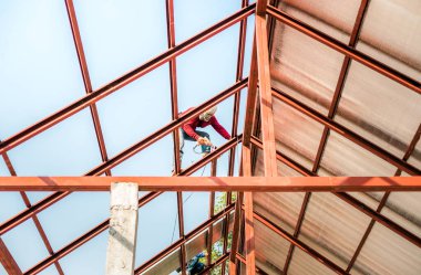 Özel koruma işinde çalışan çatıcı eldiven giyer, hava veya pnömatik çivi tabancası kullanır, yeni çatının tepesine asfalt kiremit yerleştirir, inşaat halindeki konut kavramı.