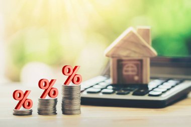 Coins and house  on the calculator And has an illustration of interest concept of calculating interest payments. planning savings money of coins to buy a home concept for property, mortgage, invest.