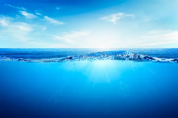 Suyun altındaki mavi dalgalar ve kabarcıklar. Sakin denizin üzerindeki güzel beyaz bulutlar güneş ışığı yansıması, sakin su yüzeyinin sakin deniz uyumu. Güneşli gökyüzü ve durgun mavi okyanus.