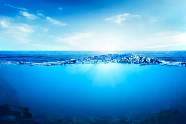 Suyun altındaki mavi dalgalar ve kabarcıklar. Sakin denizin üzerindeki güzel beyaz bulutlar güneş ışığı yansıması, sakin su yüzeyinin sakin deniz uyumu. Güneşli gökyüzü ve durgun mavi okyanus.
