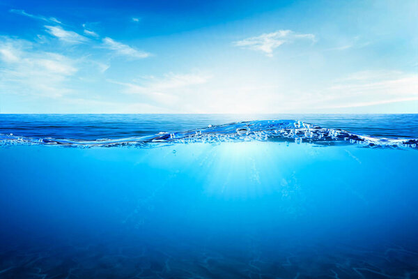 Волны и пузыри синей воды. Белые облака на голубом небе над спокойным морем с солнечным светом, спокойная морская гармония спокойной водной поверхности. Солнечное небо и спокойный голубой океан.