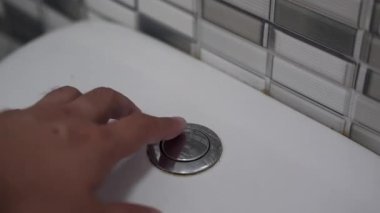 Erkek eli gümüş tuvalet düğmesine basıyor. Kavram: suyu gelecek yararlara sakla.