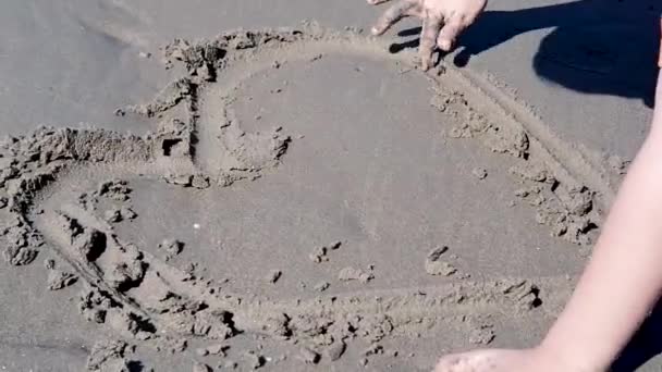 孩子们的手在沙滩上玩耍用你的手在沙滩上画出心形 — 图库视频影像
