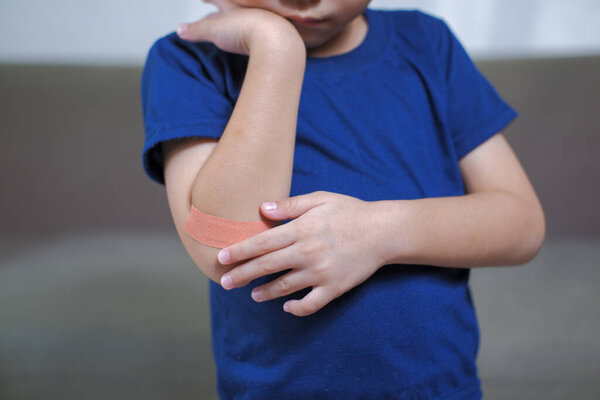A boy hurts his arm, holding his bandaged arm