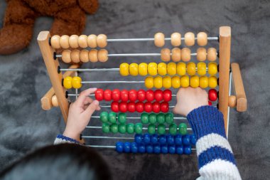 Asyalı çocuk yatakta oyuncaklarla oynuyor.