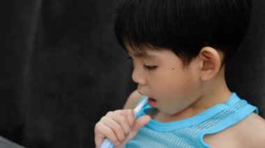Asyalı çocuk oturma odasında dişlerini fırçalıyor.
