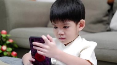 Asyalı çocuk arkadaşlarıyla çevrimiçi sınıfta cep telefonuyla iletişim kurmak için el ele tutuşuyor.
