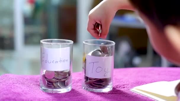 持银币的亚洲男孩选择在玩具和学习之间省钱 — 图库视频影像