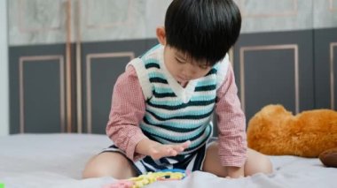 Asyalı çocuk yapbozlarla oynuyor neşeyle yatakta.