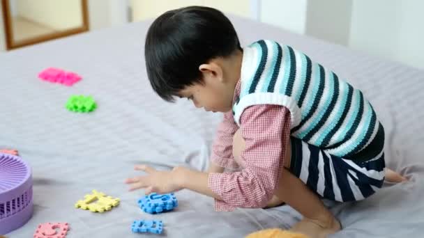 Asiatischer Junge Spielt Freudig Mit Puzzles Auf Dem Bett — Stockvideo