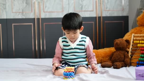 Asiatischer Junge Spielt Freudig Mit Puzzles Auf Dem Bett — Stockvideo