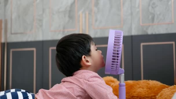 Азиатский Мальчик Лежит Матрасе Жаркий День Счастливо Играет Переносным Вентилятором — стоковое видео