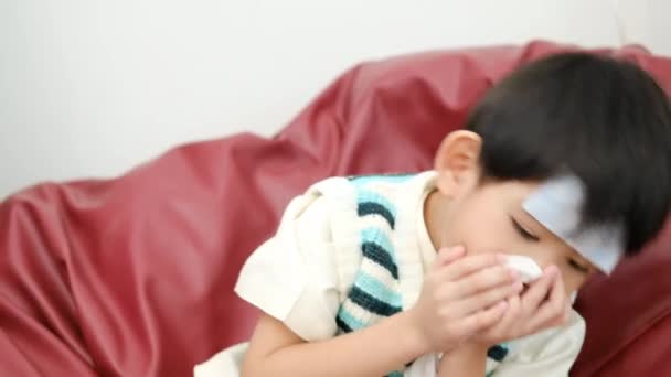 亚洲男孩因发烧躺在床上 额头上的斑斑减少了 但面带微笑 — 图库视频影像