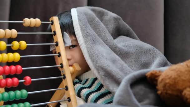 亚洲男孩病了躺在床上 额头上长了一块发热斑斑 由于感冒 他用毯子盖住了自己 — 图库视频影像