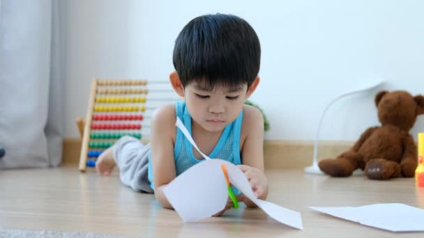 Азіатський Хлопчик Використовує Ножиці Різання Паперу Вздовж Ліній Навчання Поза — стокове відео