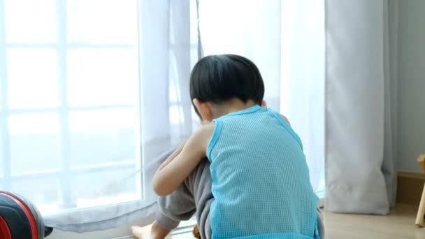 悲しいアジアの少年は頭を下に座って 彼のお気に入りの人形のドアを見る — ストック動画