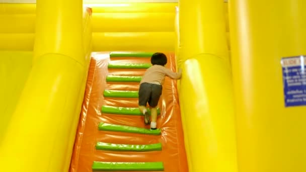 Маленький Азиатский Мальчик Поднимается Лестнице Надувную Игровую Площадку — стоковое видео