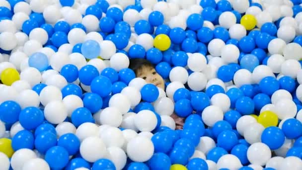 小さなアジアの少年がボールの間で隠れて探していた — ストック動画