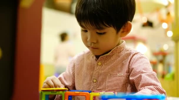 Een Kleine Aziatische Jongen Speelt Met Een Vierkante Magnetische Puzzel — Stockvideo