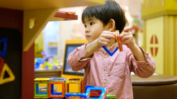Маленький Азиатский Мальчик Играет Квадратной Магнитной Головоломкой — стоковое видео