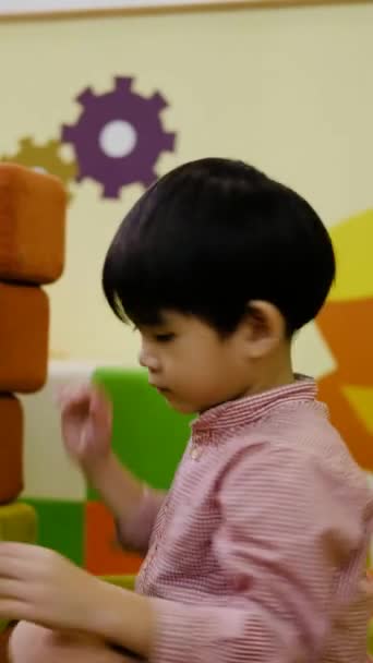 小さなアジアの少年が大きな正方形のパズルで遊んでいる — ストック動画