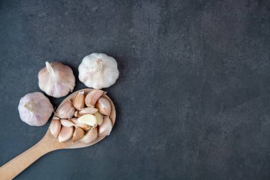 Siyah arka planda büyük ve küçük sarımsak başları.