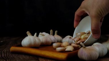 Bir adamın eli ahşap bir tabağa sarımsak karanfili döküyor..