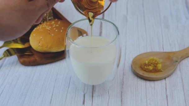 男の手がミルクのグラスに蜂蜜を注いでいる — ストック動画