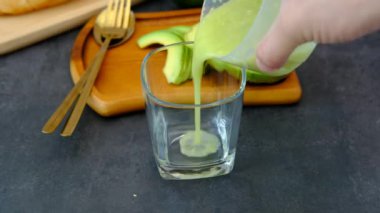 Erkek elleri meyve suyundan elde edilen avokado suyunu döküyor..