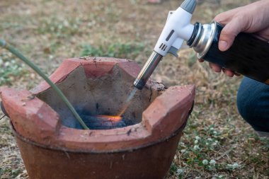 Adamın eli kömür ocağını yakıyor. Pişirmeye hazır ol.
