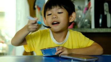 Küçük Asyalı çocuk oturmuş çikolatalı pasta yiyor.