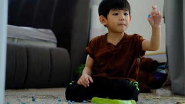 Asyalı çocuk odada plastikle oynuyor.