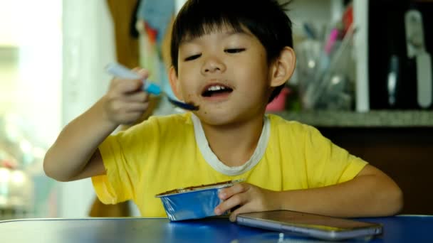 Pequeño Chico Asiático Sentado Comiendo Pastel Chocolate — Vídeo de stock