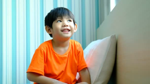 Liten Asiatisk Pojke Sitter Sängen Skrattar — Stockvideo