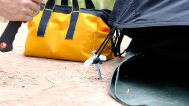 Tourists' hands use hammers to hammer into the ground to make the tents strong.