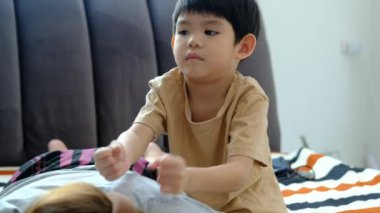 A young Asian child is taking care of his mother by massaging her muscles to relax her.