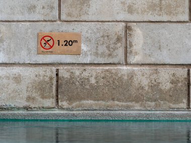 Yüzme havuzunun yan duvarına yüzme havuzu derinliği uyarısı asılır..