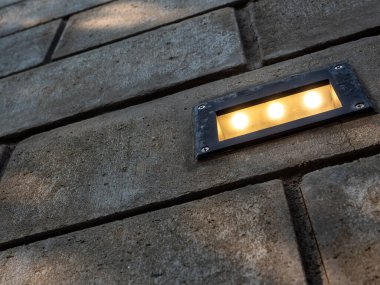 Tuğla duvarda, tavan arası süslemesi olarak açık hava lambası var.