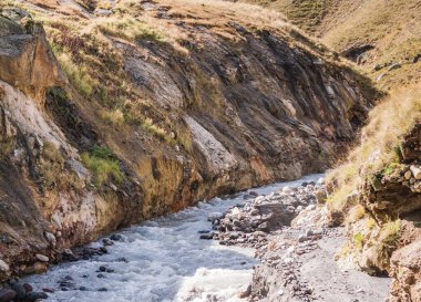 Dağ gürültülü, hızlı nehir hışırdıyor ve köpükler sarp kıyıları olan kayalık bir vadide, güneşli bir sonbahar günü dağlarda