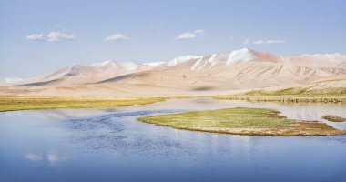 Yüksek dağ manzarası, dağlarda bir nehir bir dağ vadisinde yeşil çayırlar arasında dağların arka planına karşı akar, arka plan için Pamir Dağları 'ndaki manzara